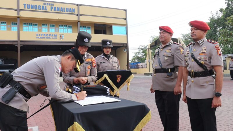 Kapolresta Banda Aceh Andi Kirana menandatangani berita acara serah terima jabatan dalam upacara sertijab Kabag, Kasat dan Kapolsek jajaran di halaman Mapolresta Banda Aceh, Jumat (27/03/2026). Foto: (Humas Polresta Banda Aceh).