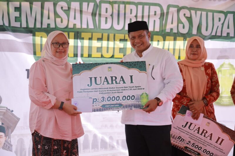 Sekda Aceh Besar, Bahrul Jamil, S.Sos., M.Si menyerahkan hadiah Pertama kepada pemenang lomba Toet Apam dan Bubur Asyura dari Dinas Diskopukmdag Aceh Besar di halaman Dekranasda Aceh Besar, Kamis (25/06/2026).