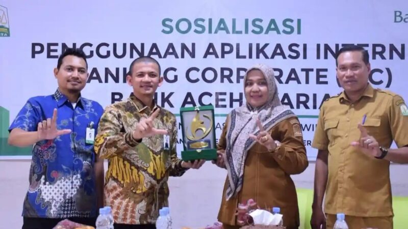 MENYERAHKAN CINDERAMATA - Pemimpin Bank Aceh Cabang Bireuen, Feri Kurniawan (kedua kiri) didampingi Staf Digitalisasi Bank Aceh Pusat, Iqbal, menyerahkan cinderamata kepada Plt Kacabdin Bireuen, Yusnita, yang didampingi Kasi Manajemen, Guru, Tendik, dan Mutu Kesiswaan Cabdin Bireuen, Zulfikri dalam acara sosialisasi penggunaan aplikasi IBC Bank Aceh, di SMA Negeri 1 Bireuen, Selasa (22/9/2026).